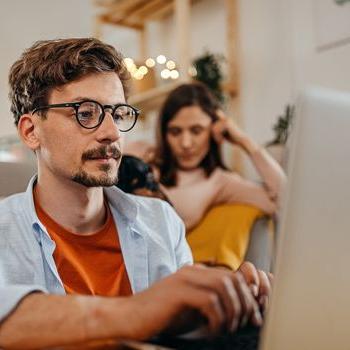 A man in glasses applies online for the Patelco Points Rewards Credit Card.